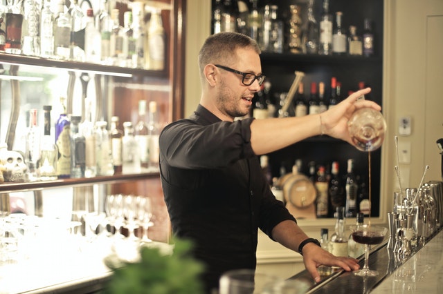 Man Pouring a Drink Standing Behind a Bar