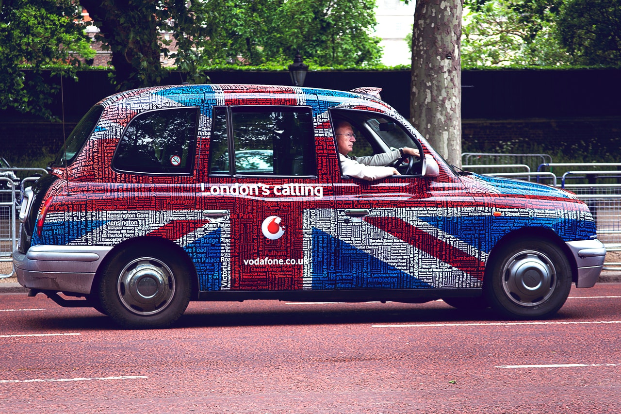 Man Driving British Union Flag Painted London Taxi Near Tree